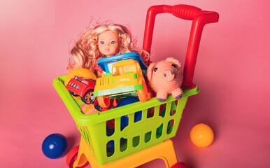 Colorful toy shopping cart with dolls, cars, and animals sitting on a pink background
