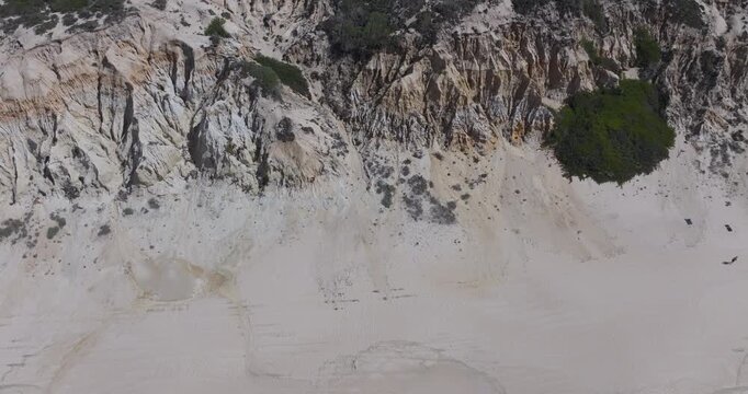 Close aerial view of eroded coastal cliffs revealing layered rock strata textures and natural patterns on the wild Alentejo coast, Portugal