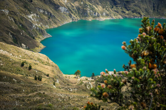View of the vivid turquoise waters of Quilotoa Lake nestled within rugged, layered cliffs and sparse vegetation, Quilotoa lake, Cotopaxi province, Ecuador.