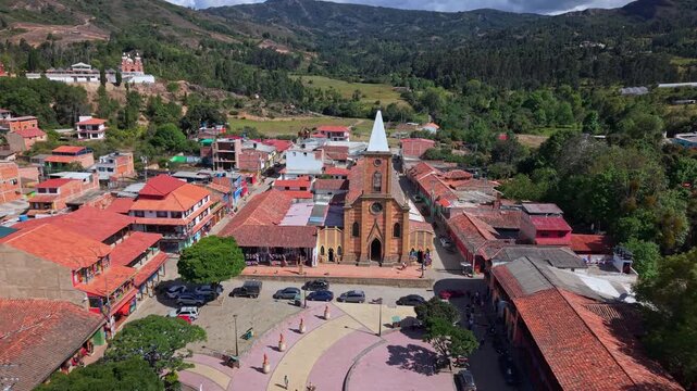 Aerial drone reveal of Iglesia de R&aacute;quira and the central plaza in R&aacute;quira, Colombia, captured on a bright sunny day, showcasing colonial architecture and the charming atmosphere of this cultural town