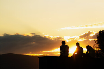Silhouette group of friends enjoying sunset moment on holiday weekend