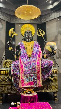 Shani Dev in seated posture, featuring a golden halo, trishul, and traditional attire. 