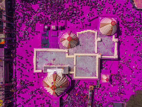 Aerial view of a temple bathed in vibrant magenta powder, surrounded by devotees in a sea of color during a festive celebration, Jyotiba Dongar, Maharashtra, India.