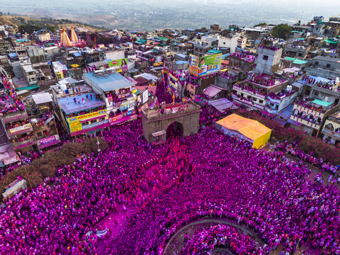 Aerial view of a vibrant sea of pink powder blanketing a packed gathering near the ancient Jyotiba Temple, a spectacle of cultural immersion, Jyotiba Dongar, Maharashtra, India.