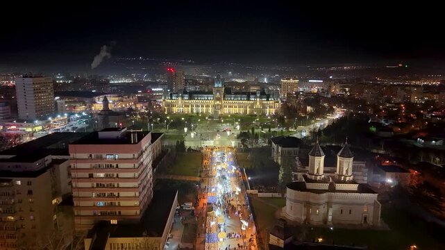Night drone showing grand Palace of Culture and long illuminated Stefan cel Mare boulevard full of holiday crowds, Iasi