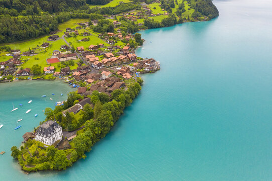 Aerial view of the turquoise lake embracing the village and castle, a symphony of blues and greens, Iseltwald, Canton of Bern, Switzerland.