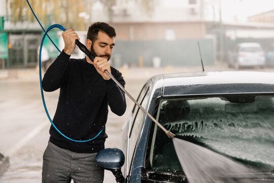 Professional pressure washing car exterior at car wash