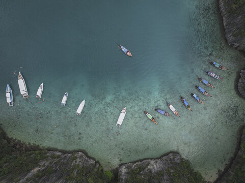 Aerial view of boats resting on the turquoise water, surrounded by rocky green cliffs, Ao Nang, Krabi, Thailand.