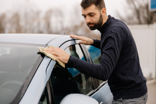 Careful auto detailing of car windshield outdoors