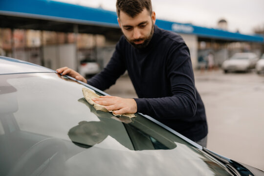 Car wash business worker polishing vehicle window