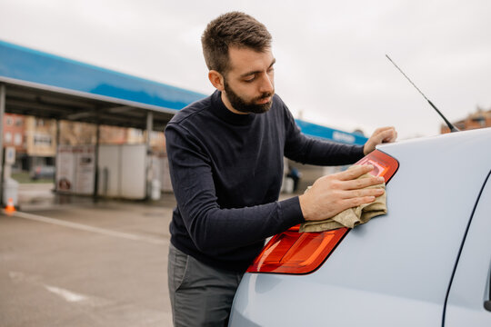 Car wash employee cleaning vehicle with microfiber cloth