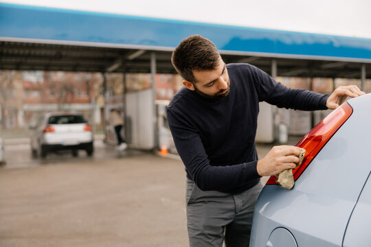 Car care concept with man cleaning vehicle windshield