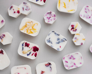 handmade wax sachets with embedded dried flowers on a light gray background. Ideal for illustrating...