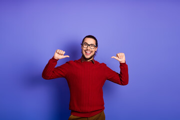 Young handsome man with glasses in a red sweater smiles points to himself violet purple background...