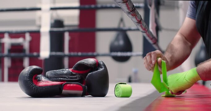 Close-up 4k video of a male fighter wrapping green hand bandages for boxing workout. Focused and steady, the boxer wraps bright yellow hand wraps, gearing up for rigorous training.