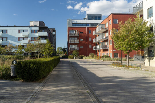 View of the pathway lined with trimmed bushes leads to the colorful buildings under a bright blue sky, Vastra Hamnen, Malmo, Sweden.