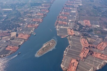 Aerial view of brick kilns sprawl along the riverbanks, casting a stark contrast against the blue waters, Dhaka, Dhaka Division, Bangladesh.