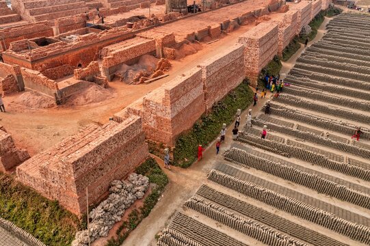 Aerial view of workers carrying baskets across the brick factory, the red-brown bricks contrast with the workers' colorful clothing, Dhaka, Dhaka Division, Bangladesh.