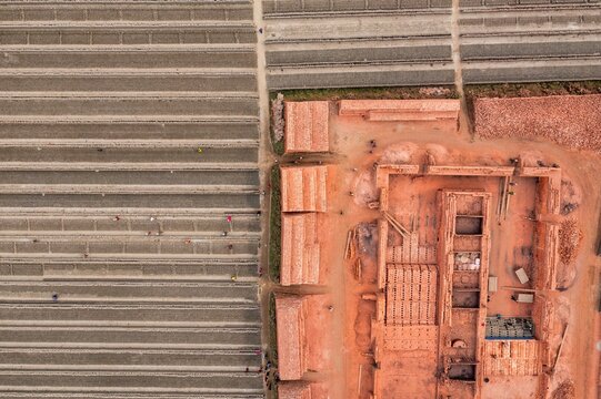 Aerial view of brick kilns and stacked bricks create a textured landscape, displaying earth tones and industrial patterns, Dhaka, Dhaka Division, Bangladesh.