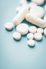 Various white pills on blue background against backlight.