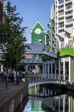 View of a vibrant green clock tower rises above a bridge over a canal reflecting the urban landscape, a modern symphony of color and form, Zaandam, North Holland, Netherlands.
