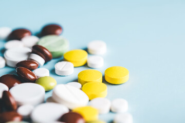 Various pills on blue background, angle view.