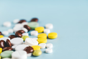 Various pills on blue background, angle view.