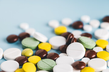 Various pills on blue background, angle view.