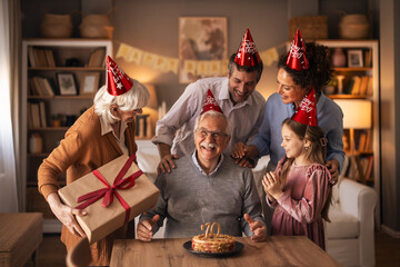 Joyful Family Birthday Celebration With Grandfather, Gifts, Cake, And Party Hats In A Cozy Home