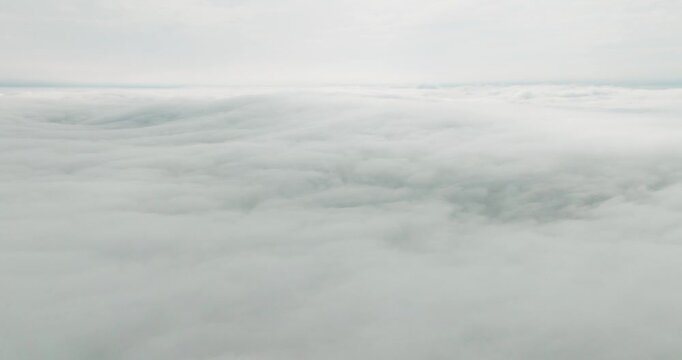 Aerial view of fluffy, undulating clouds blanketing the sky, creating a serene, ethereal atmosphere above Fugloy, Faroes.