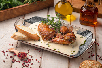 Traditional Georgian chkmeruli chicken fried and served in creamy garlic sauce with bread on a rustic plate