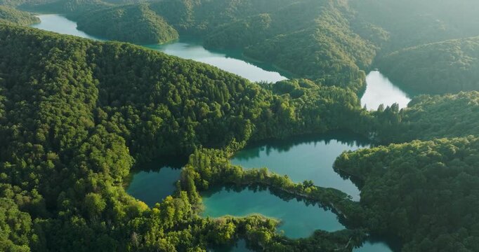 Aerial view of the vibrant waters weaving through the dense green forests creating a stunning natural landscape, Plitvice, Croatia.