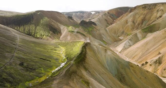 Aerial view of Landmannalaugar's dramatic landscape, where vibrant green valleys meet ochre mountains, creating a stunning contrast, Landmannalaugar, Iceland.