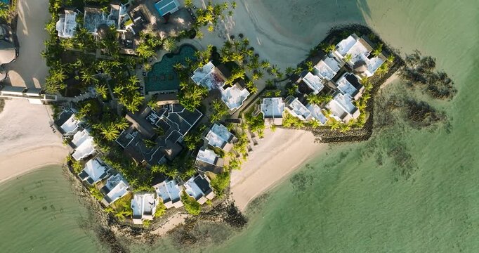 Aerial view of Shangri-La resort with white roofed villas, pools, and palm trees on the coast with turquoise waters, Shangri-La, Mauritius.