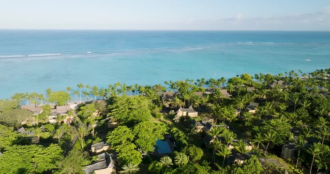 Aerial view of the turquoise ocean meeting the lush green coastline dotted with buildings, Trou aux Biches, Mauritius.
