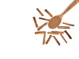 Cinnamon powder on wooden spoon and dry cinnamon on white background. Flat lay 