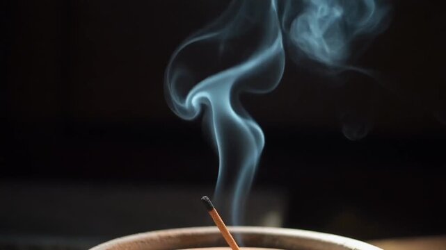 A close-up of incense smoke rising from a holder.