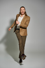 Stylish man embraces elegance in beige blazer against a grey backdrop