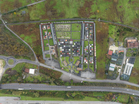 Aerial view of a cemetery with orderly rows of graves and tombs, contrasting with the surrounding autumnal landscape, Serino, Irpinia, Italy.