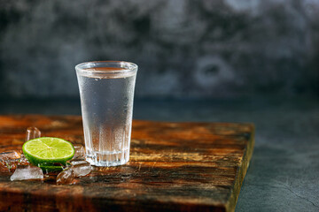 Vodka. Shots, glasses with vodka with ice and lime on gray background