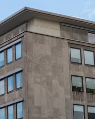 Modern building facade with large windows and rooftop balcony in an urban setting