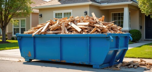 Large blue dumpster filled with wood debris on residential driveway. Construction waste container for junk removal, disposal. Home renovation house cleanup project with garbage collection. Building