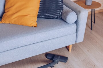 A Cozy Living Room Scene Featuring a Grey Sofa with Decorative Cushions and a Vacuum Cleaner, Reflecting a Clean and Inviting Space.