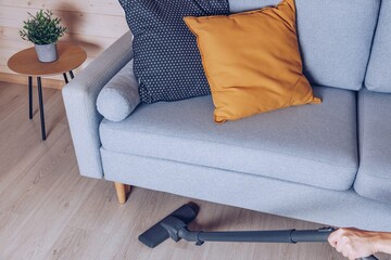 A Cozy Living Room Scene Featuring a Sofa, Cushions, and Vacuuming Process for a Clean Home Environment