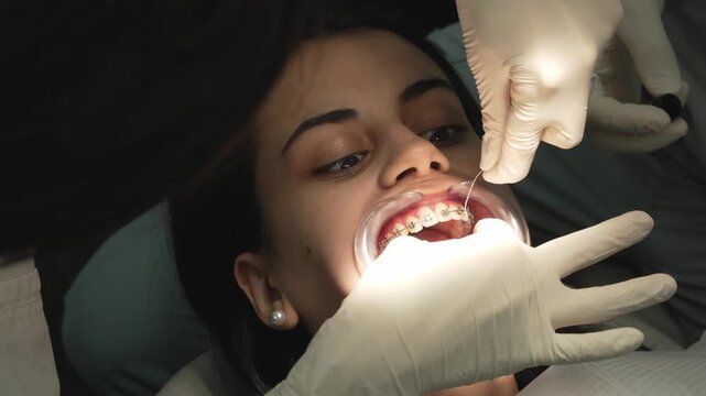 Orthodontist placing archwire on female patient's braces during dental procedure