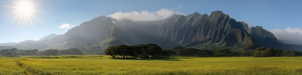 Obraz premium Majestic mountain range under clear blue sky with lush green meadow and sunburst