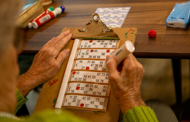 Older person playing a game of bingo using a dabber