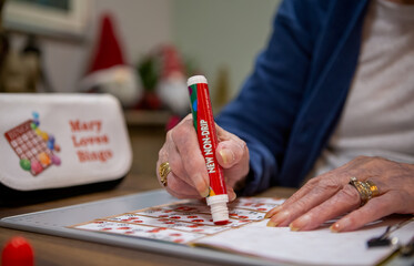 Older person playing a game of bingo using a dabber