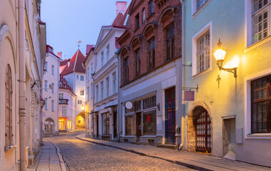 Fototapeta premium Historic cobblestone street with colorful buildings at dawn in Tallinn Old Town, Estonia