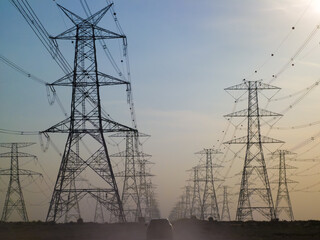Car at Empty road upon Electricity tower with stormy sky in background and SUV driving down road Electric transmission tower pylons stretching across. AERIAL View of High voltage power line Background